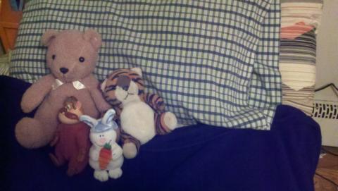 A bed with stuffed animals on a pillow.