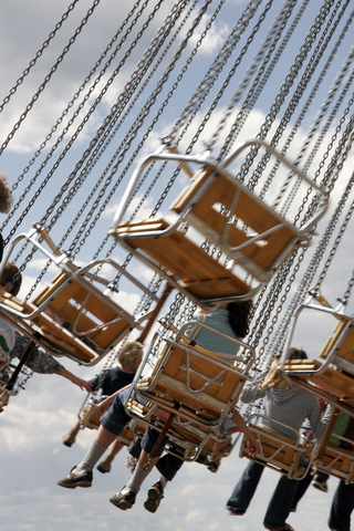 photo of a carnival swing ride - several swings suspended in air, viewed from behind