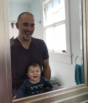 Dad and baby looking at each other in a mirror and laughing